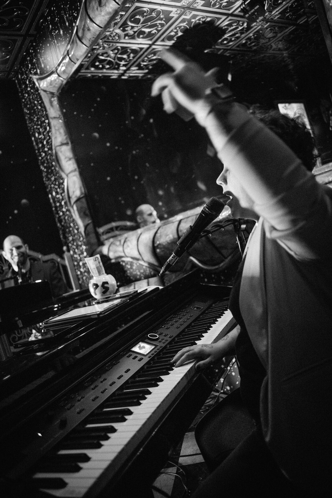 Black and white close-up of a performer singing while playing piano